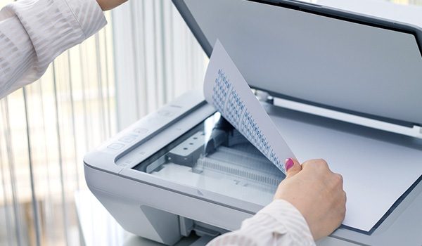 A person carefully placing papers on the scanner bed