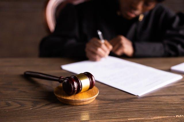 juiza assinando documento - source - https://www.pexels.com/pt-br/foto/pessoa-mesa-borrao-mancha-6077447/
