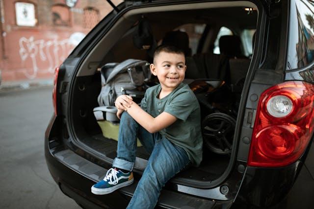 criança indo viajar - source - https://www.pexels.com/pt-br/foto/homem-de-camiseta-cinza-com-gola-redonda-e-jeans-azul-sentado-no-carro-preto-6182656/